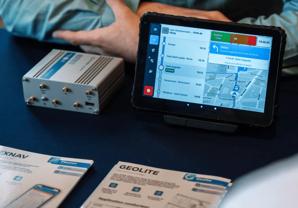 Tablette conducteur Hubup affichant la ligne 028 et son guidage, à côté d’un routeur embarqué et des brochures Flexnav et Geolite